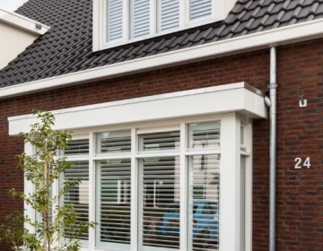 Buitenaanzicht witte shutters in erker