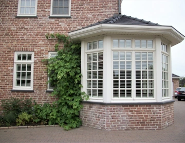 Buitenzicht erker met witte shutters