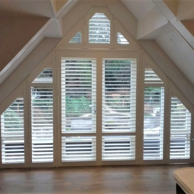 Witte shutters voor groot driehoekig raam
