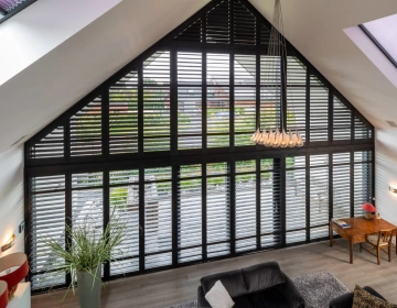 Woonkamer met shutters voor groot schuin raam