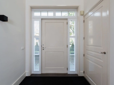 Witte shutters bij voordeur van entree