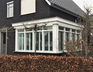 Buitenaanzicht van groot huis met shutters in erker