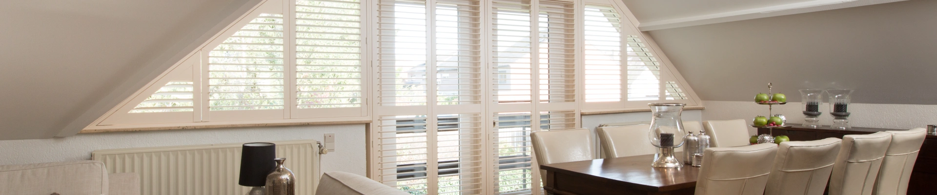Groot raam met schuine witte shutters