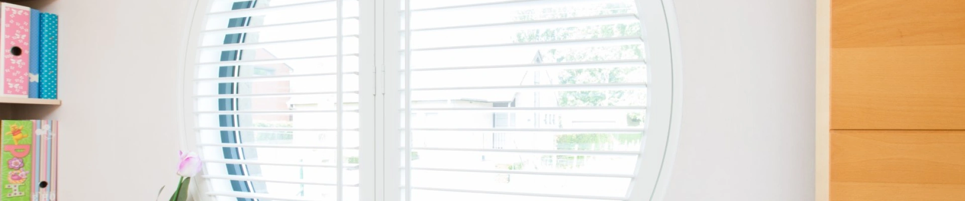 Witte shutters in klein rond raam