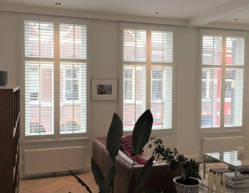 Witte shutters met tilt rod bediening in woonkamer