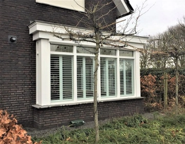 Buitenaanzicht van witte shutters in erker