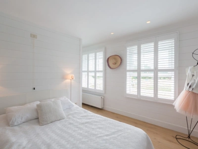 Slaapkamer met witte houten shutters