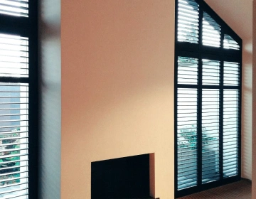 Zwarte shutters voor schuin raam in woonkamer